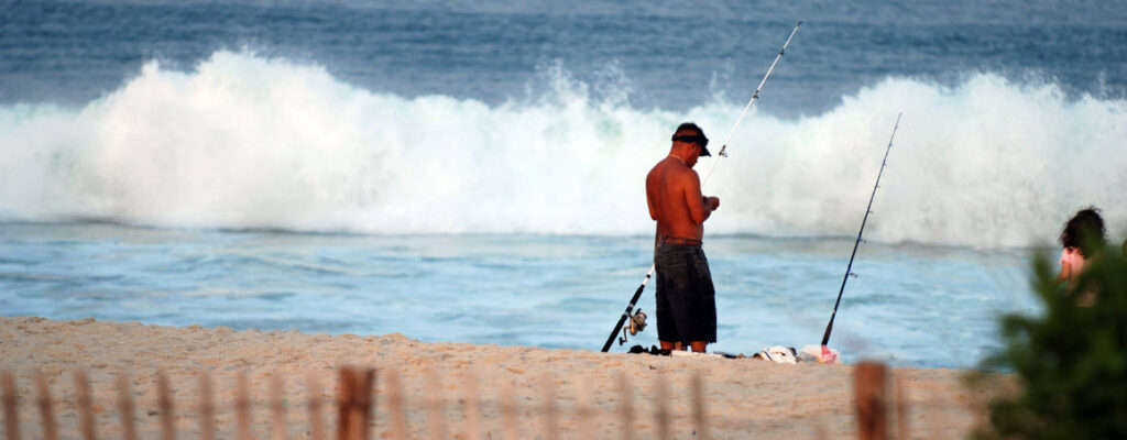 What Equipment Do I Need For Surf Fishing - man setting bait on beach
